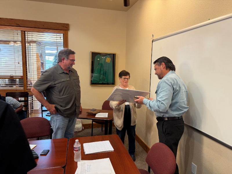 Three individuals are engaged in a discussion around a table in a conference room
